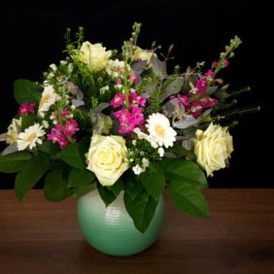 Bouquet with a variety of multicolored flowers in a rustic vase on wooden background